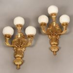 A Large Pair of Early 20th Century Gilt Bronze Three Light Arm Sconces and White Glass Globes