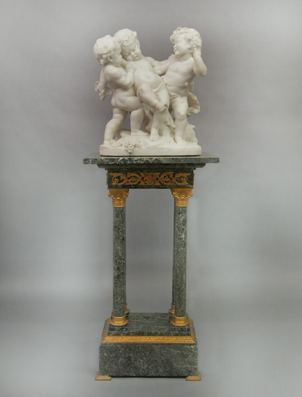 19th century Carrara Marble Figural group of Drunken Silenus seated on a tall and thin green and gold table.